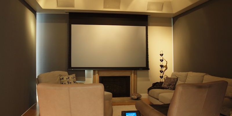Marin Custom Home Theater-Showing a picture of all the light block shades down and the projection screen dropped in front of the Plasma TV. Controlled by the Crestron touch panel on the table.